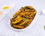 Zucchine gratinate al forno, dorate e croccanti, servite in un piatto ovale con rosmarino fresco. Accanto, ciotoline con pangrattato e olio.