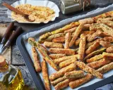 Fettine dorate di chips di zucchine pronte per essere gustate, su una teglia da forno.