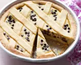 Deliziosa torta ricotta e cioccolato con decorazione a griglia e gocce di cioccolato. Una fetta è stata tolta, rivelando il ripieno cremoso.