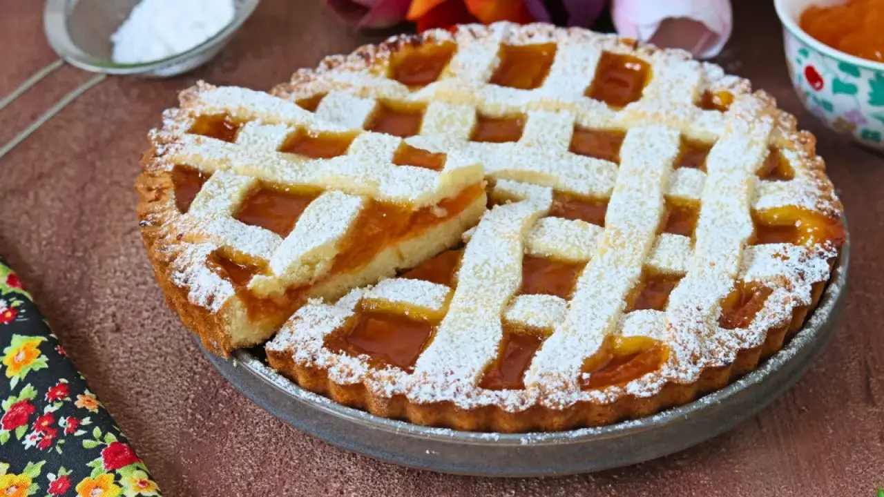 Una deliziosa crostata di marmellata, con una fetta sollevata, cosparsa di zucchero a velo.