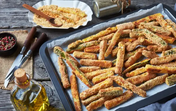 Fettine dorate di chips di zucchine pronte per essere gustate, su una teglia da forno.