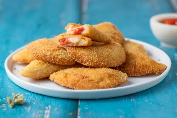 Sofficini fatti in casa dorati e croccanti, ripieni di pomodoro e formaggio filante, pronti per essere gustati.